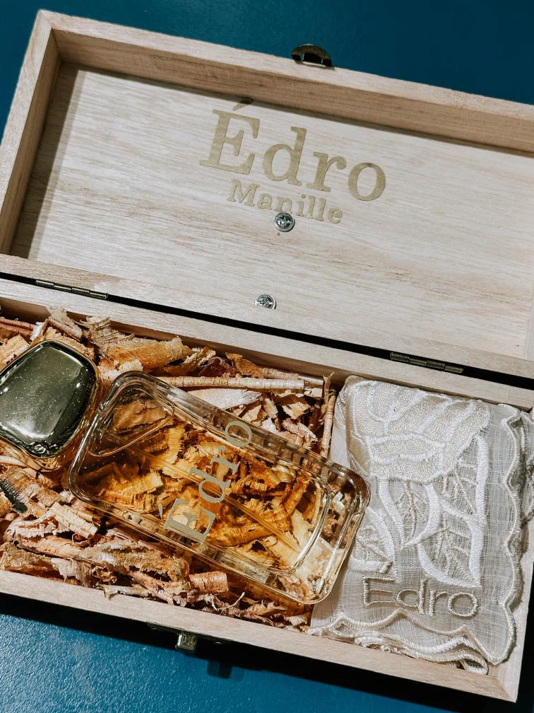 A wooden box, displaying a bottle of Edro Manille perfume, showcasing elegant packaging.
