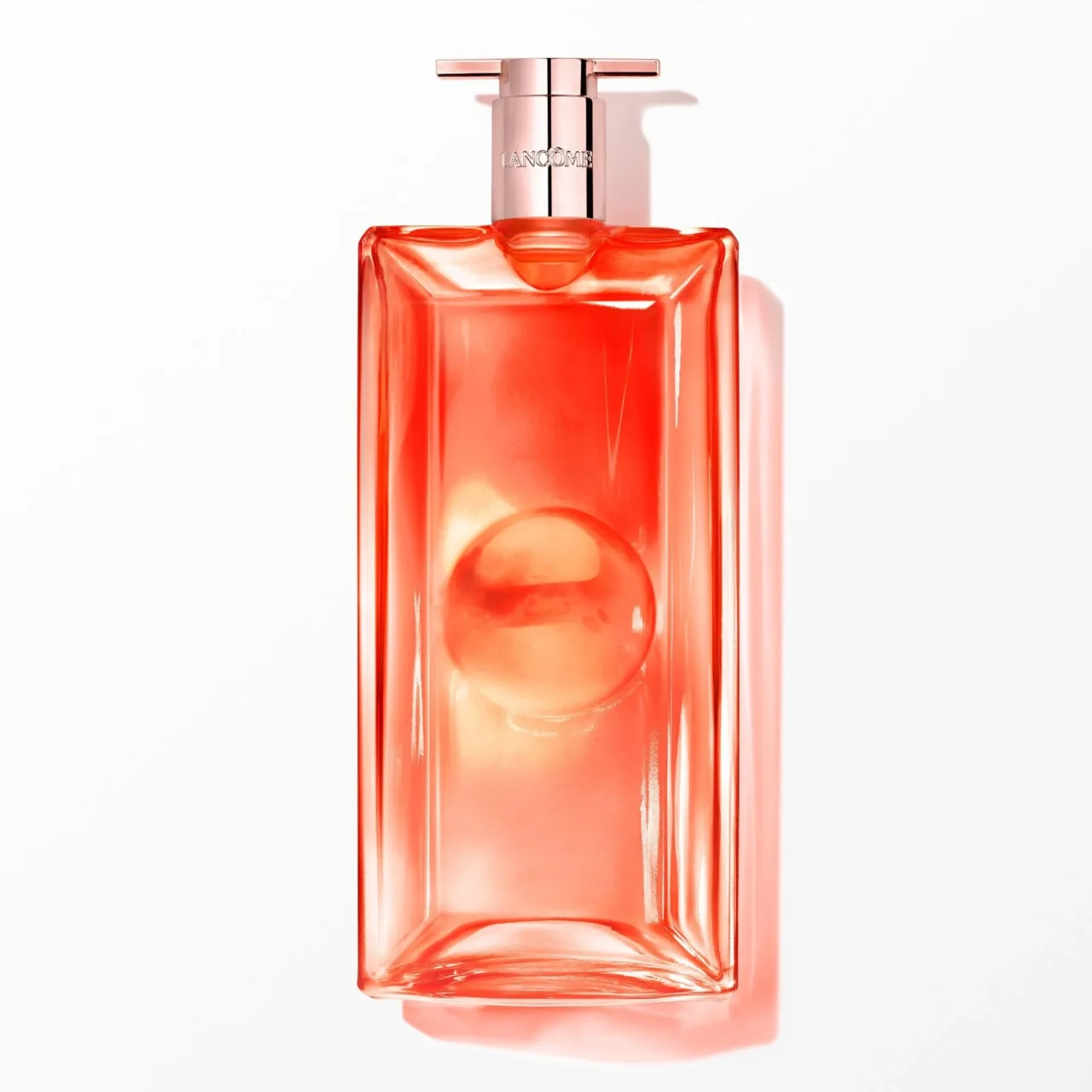 Close-up of a pink glass perfume bottle with a silver pump and the Lancôme logo on the cap against a white background.