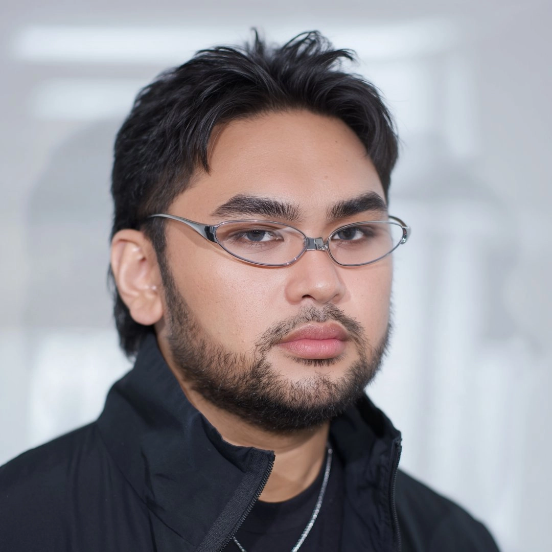 Portrait of a man with glasses and a beard, wearing a black jacket, looking at the camera.