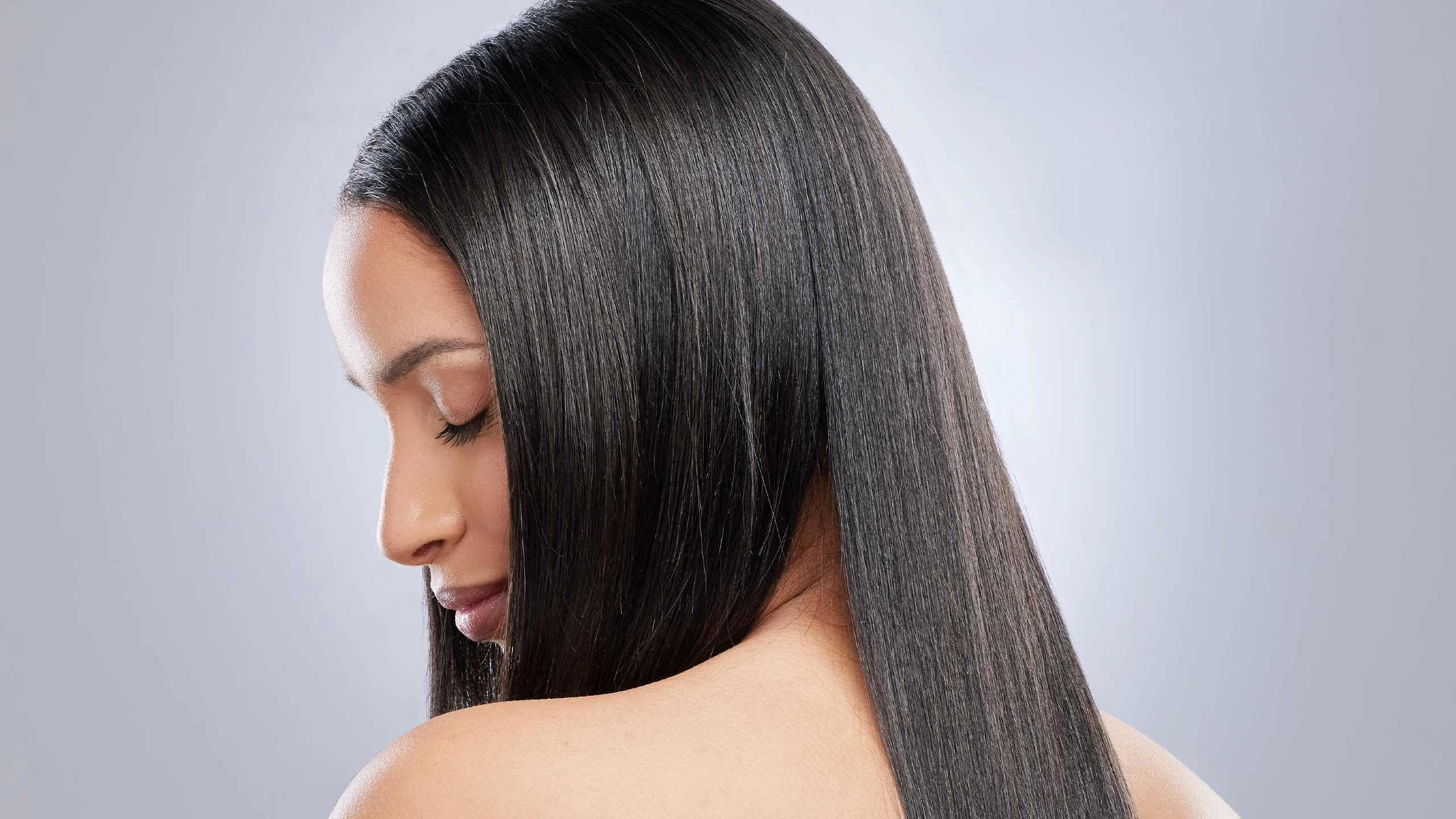 Side profile of a woman with long, sleek, straight black hair cascading over her shoulder.