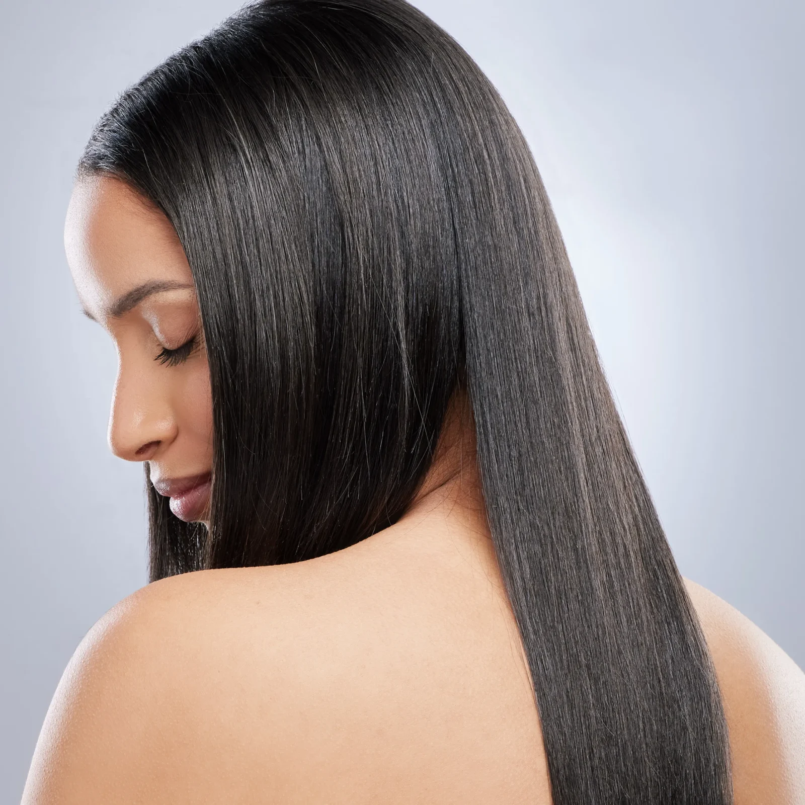 Side profile of a woman with long, straight, glossy black hair resting over her shoulder.