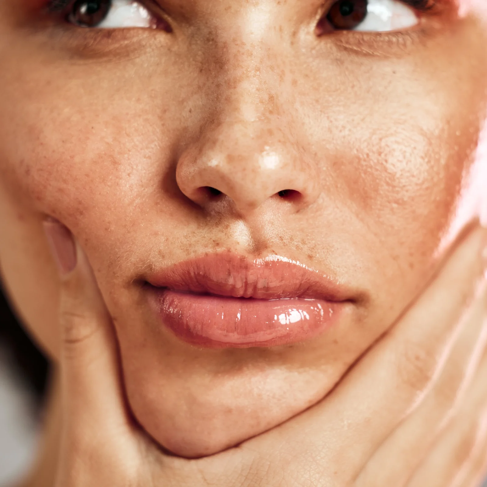 Close-up of a smiling person's mouth and chin with freckled, textured skin on the cheeks and around the lips.