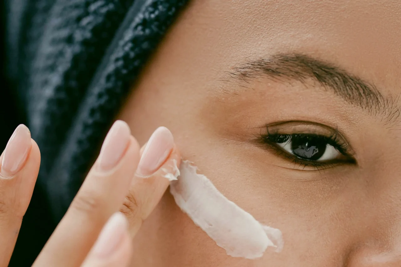 Close-up of a person wiping their nose with a tissue, showing one eye and eyebrow in the frame