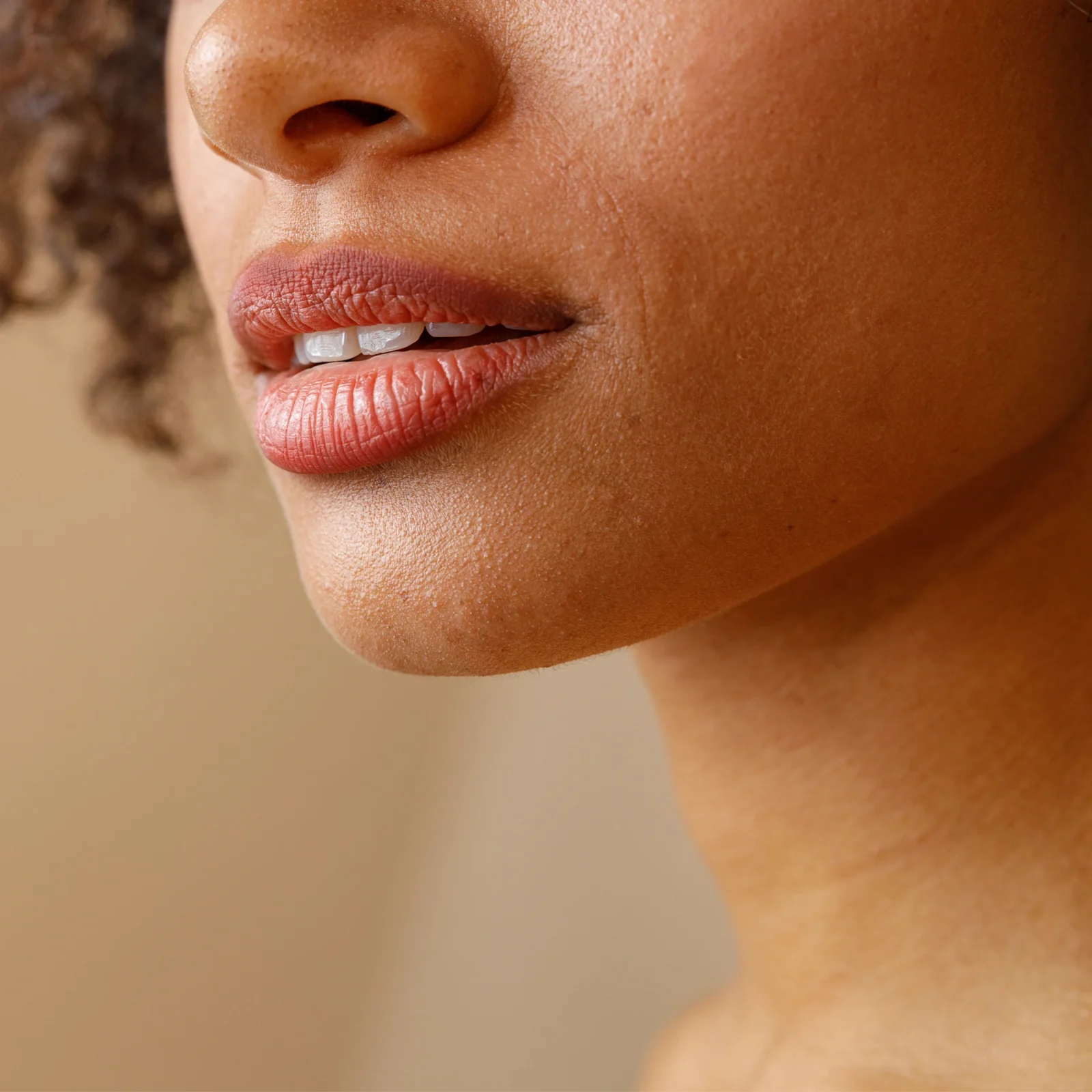 Close-up of lips and lower nose on a woman's face, showing slightly parted pink lips and textured skin.