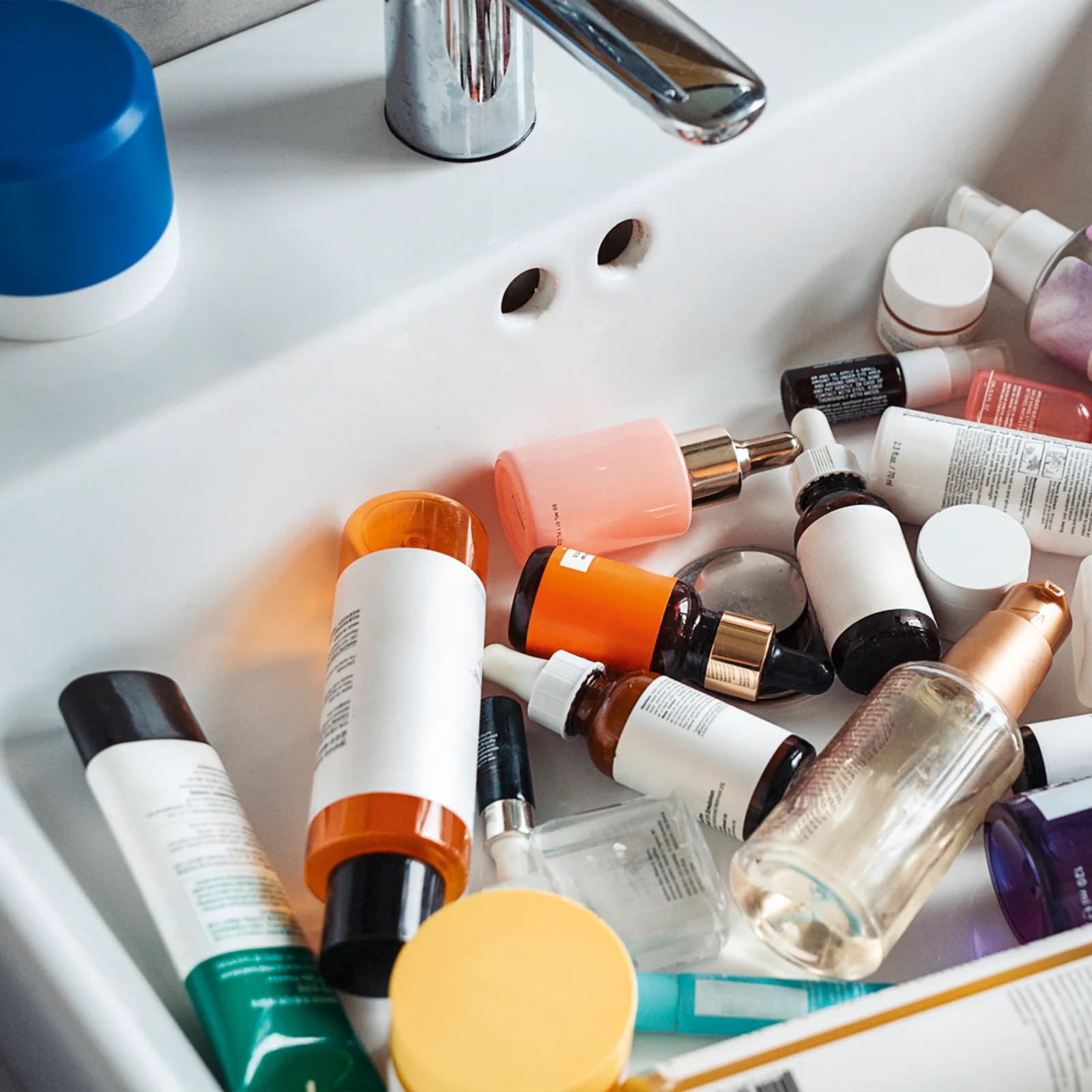 Assorted skincare tubes, bottles, and jars scattered in a white tray.