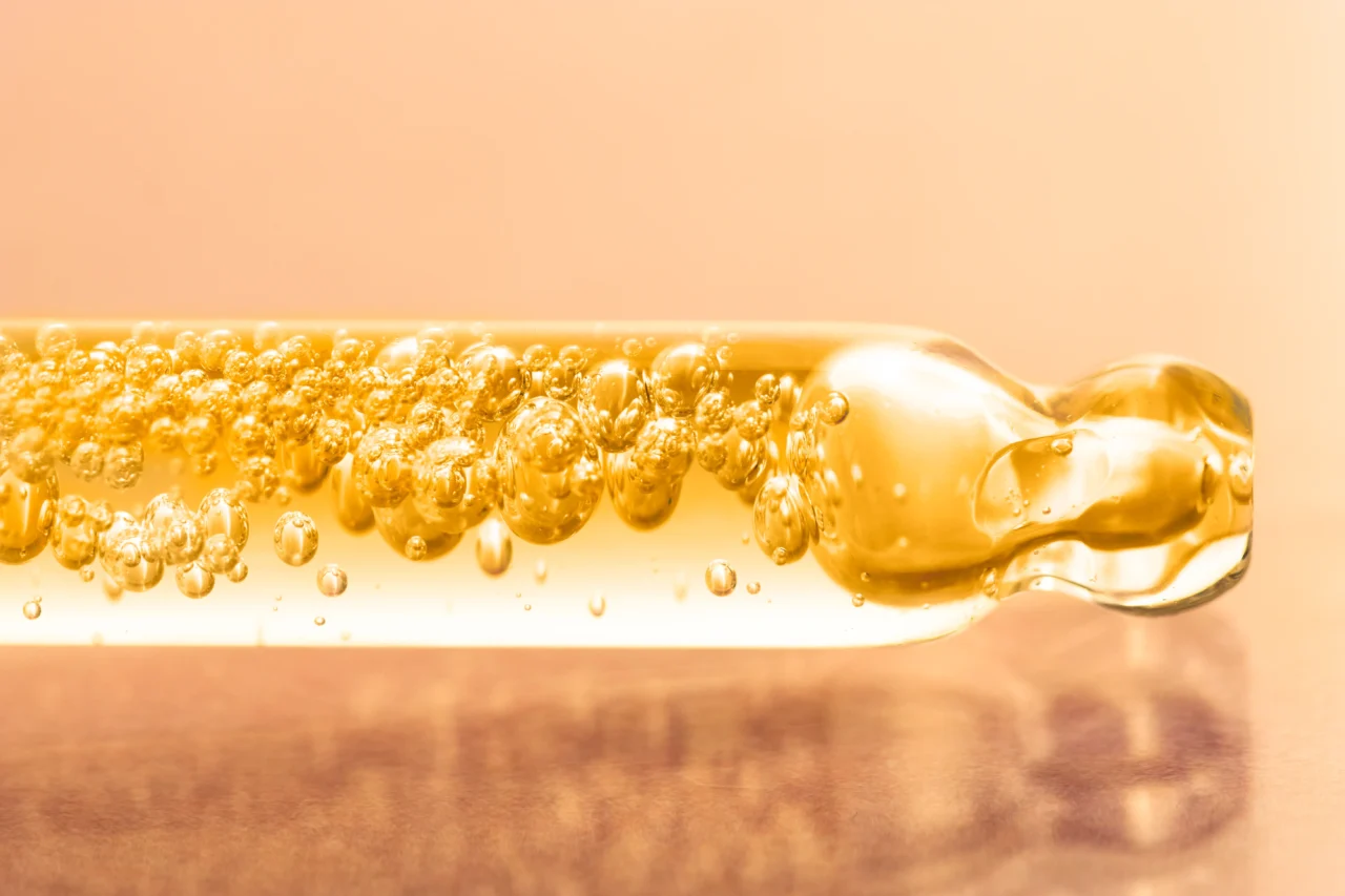 Close-up of a golden, bubbly sparkling liquid with many bubbles against a warm peach background.