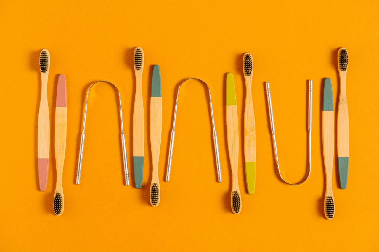 Row of colorful bamboo toothbrushes arranged vertically on an orange background, showing varied bristle colors and handle accents.